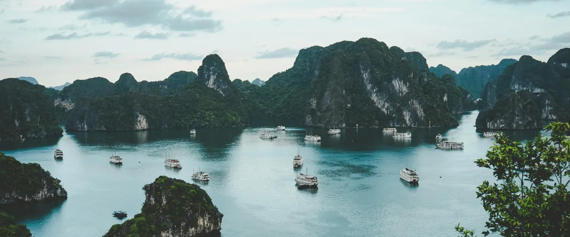 Boats sit in blue water surrounded by mountainous islands in Vietnam